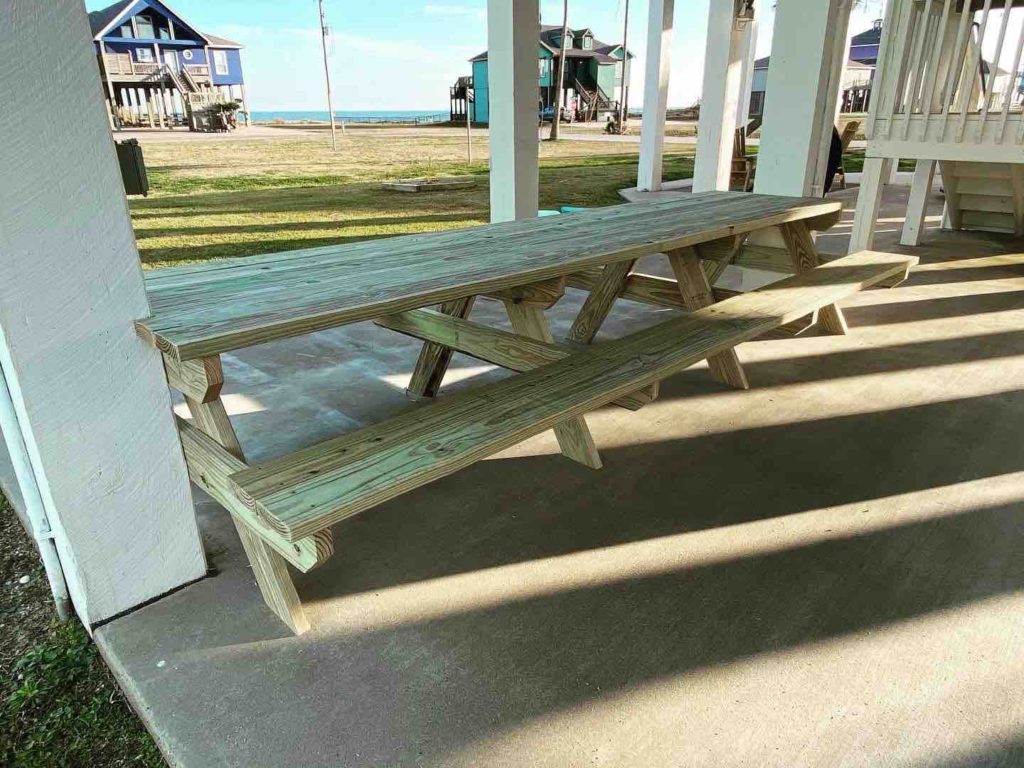 long picnic table between pilings beach